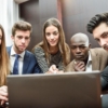 Coworkers surrounding a computer meeting.