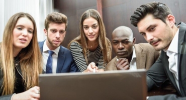 Coworkers surrounding a computer meeting.