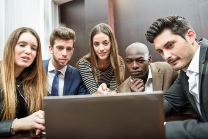 Coworkers surrounding a computer meeting.