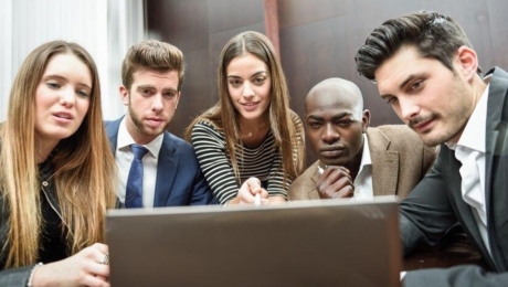 Coworkers surrounding a computer meeting.